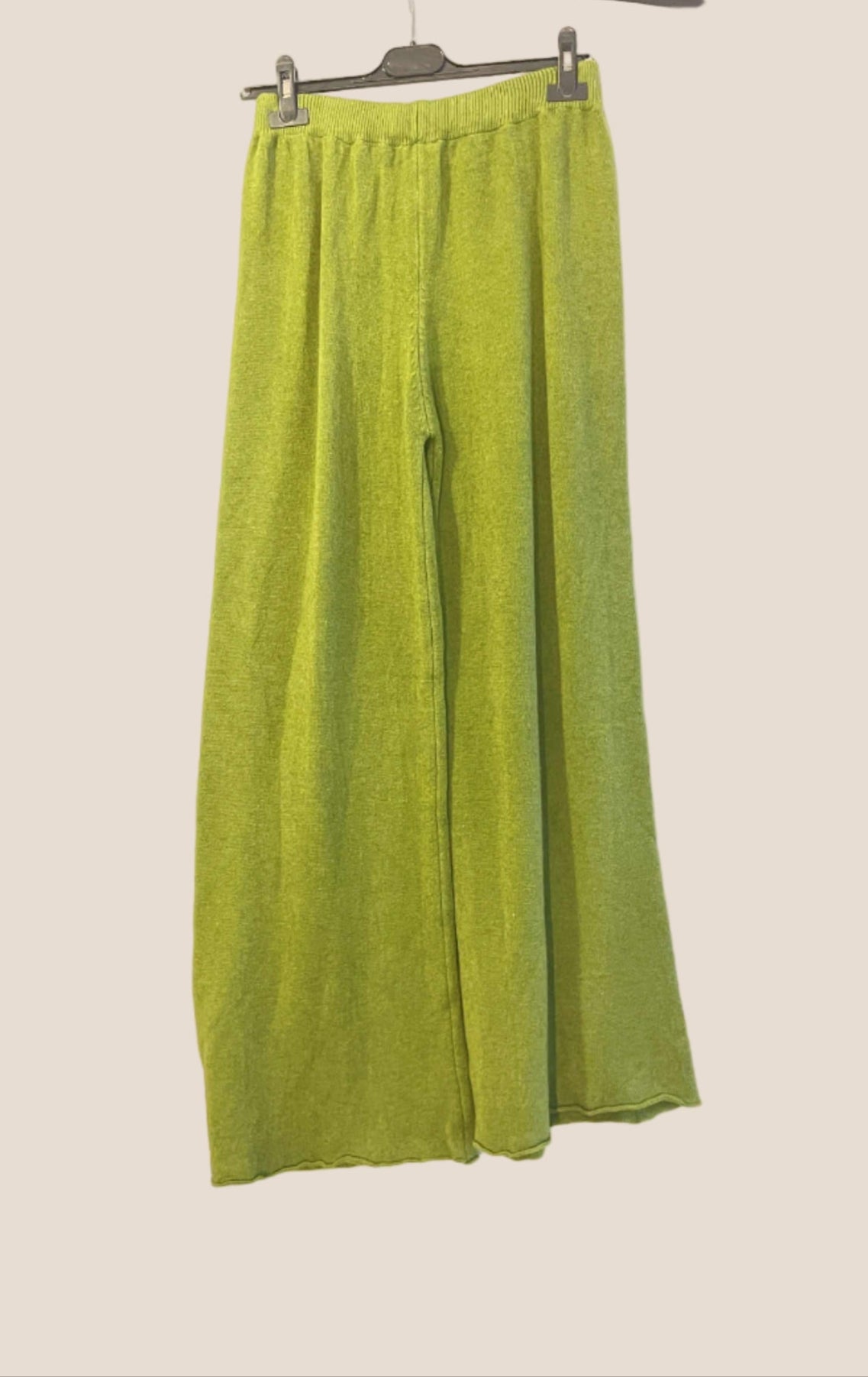 Green fabric on a hanger against a neutral background