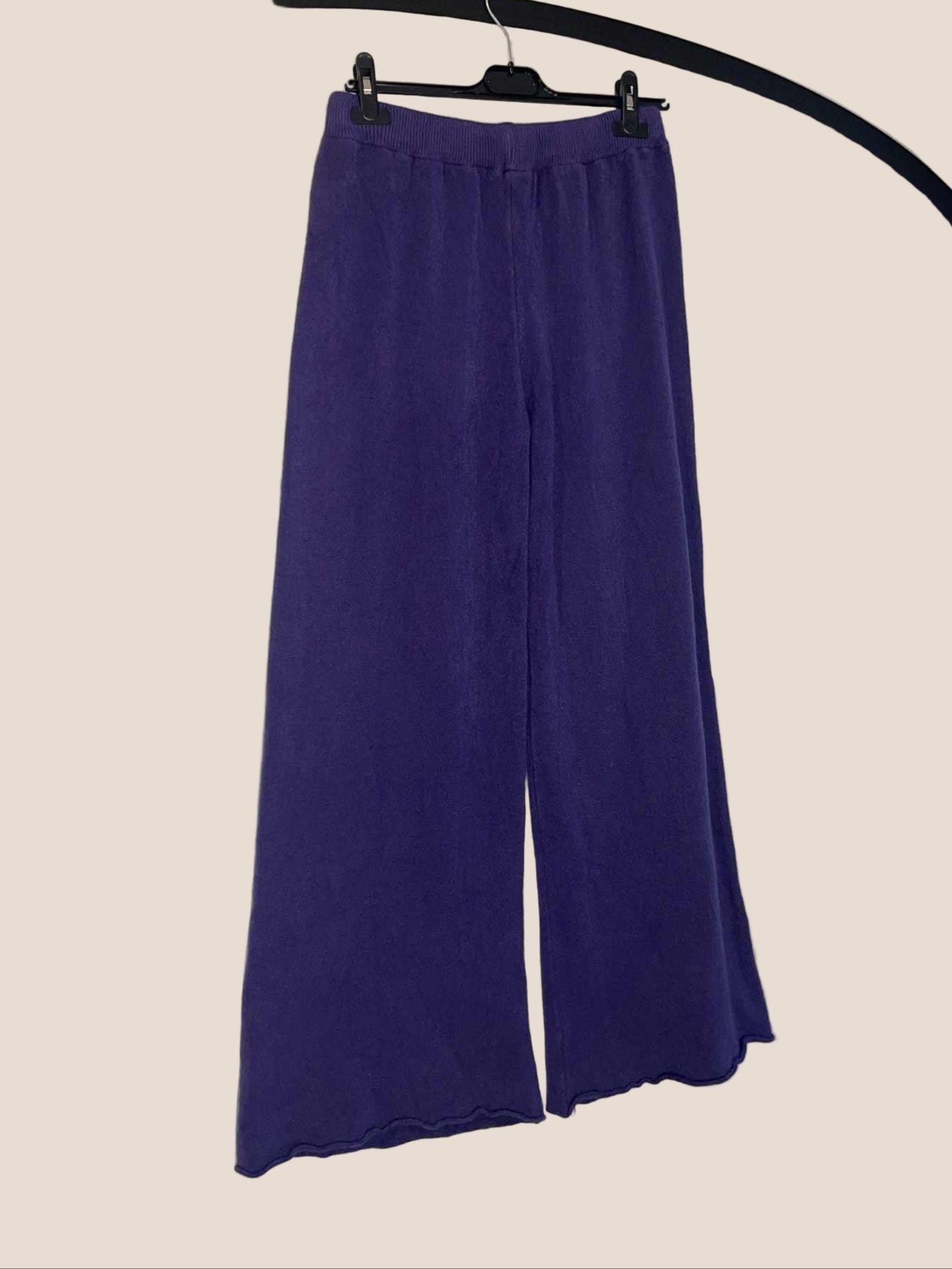Purple wide-leg pants on a hanger against a white background