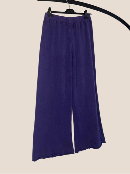 Purple wide-leg pants on a hanger against a white background